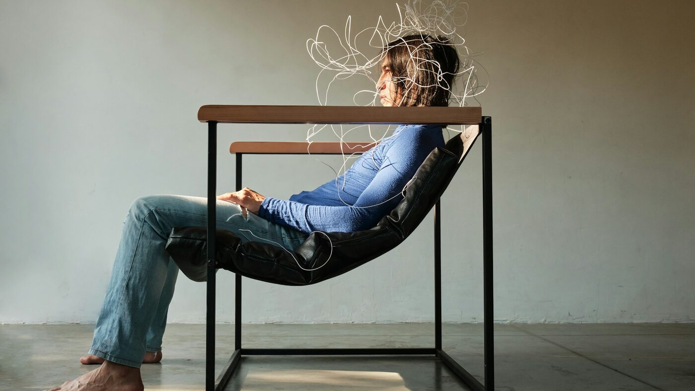 A person sitting with a tangle of lines drawn around their head, representing nervous system stress